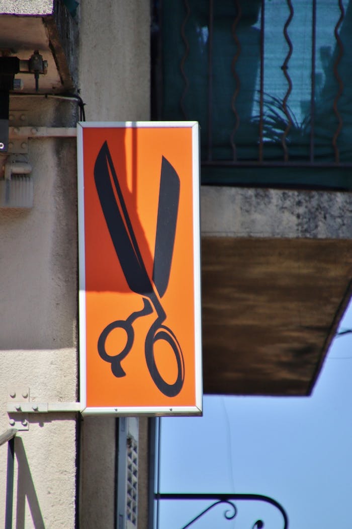 ours-journey Bright orange sign with black scissors icon for a hair salon in Cagnotte, France.