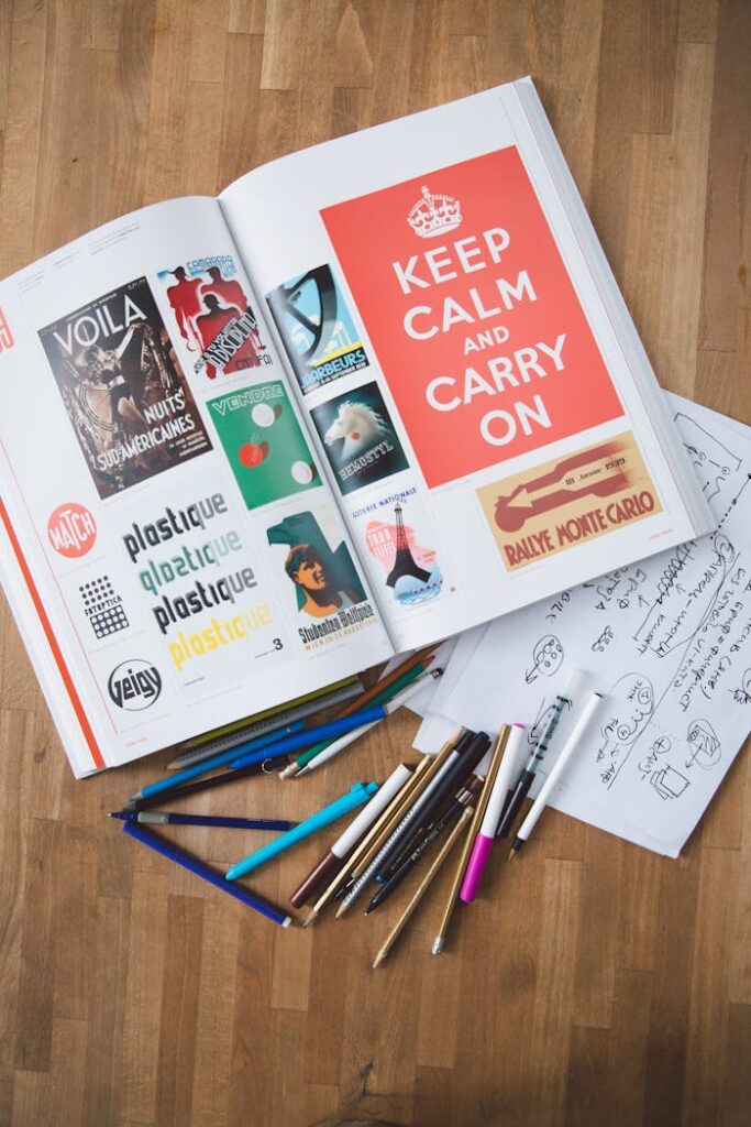 Open book with design elements and pencils on a wooden desk, perfect for creative projects.