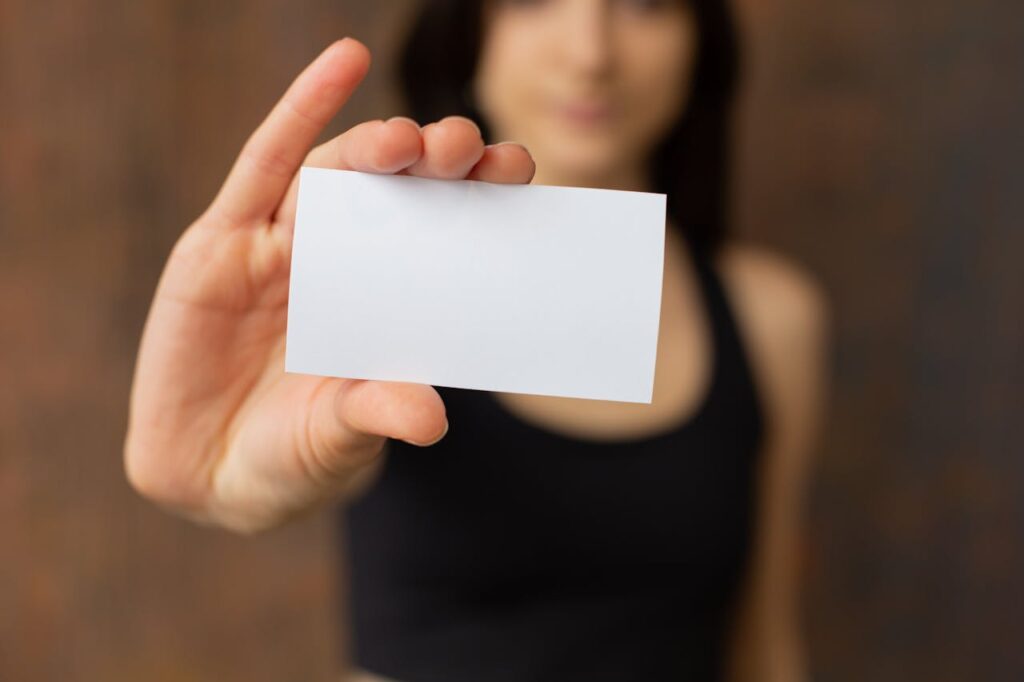 Close-up of a woman holding a blank business card with a focus on the card, perfect for customization.